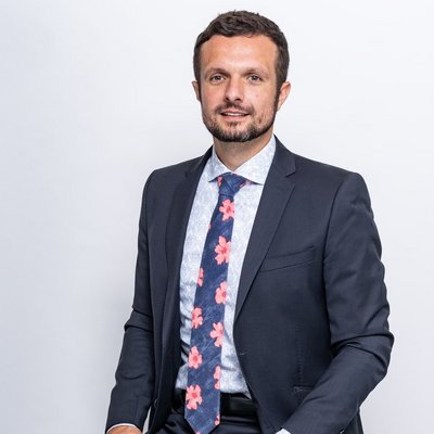 Muž sediaci v obleku s kvetovanou kravatou