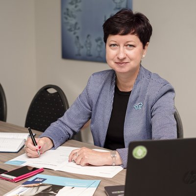 Žena s krátkymi vlasmi v károvanom saku pri podpise zmluvy