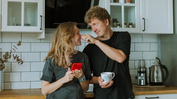 Žena a muž stojaci v kuchyni sa smejú - spoločný účet