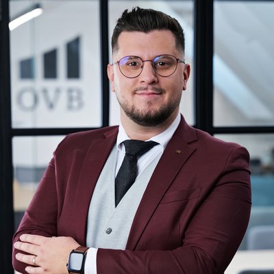 Muž v obleku pred logom OVB