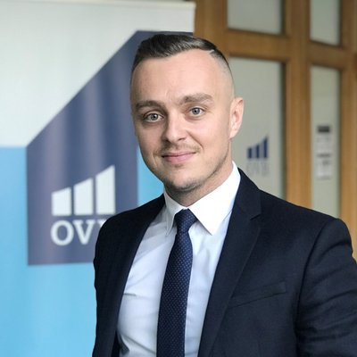 Muž v saku pred logom OVB