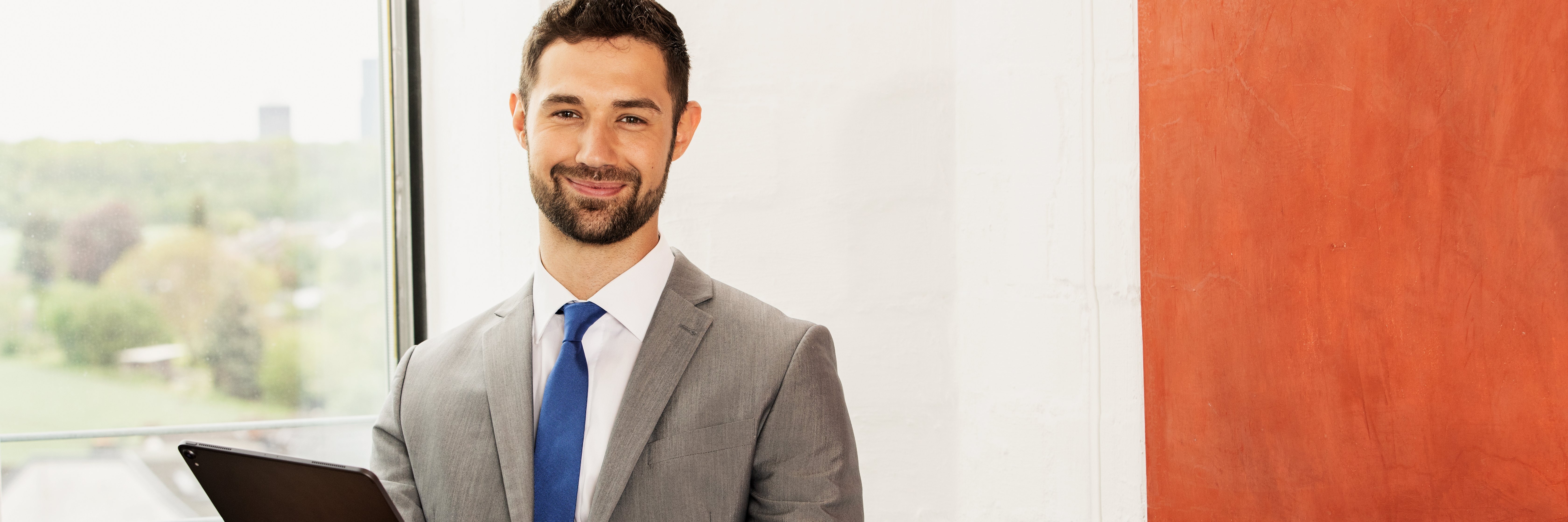 Mladý finančný poradca v kancelárii sa usmieva do kamery. Mladý finančný poradca v kancelárii sa usmieva do kamery.