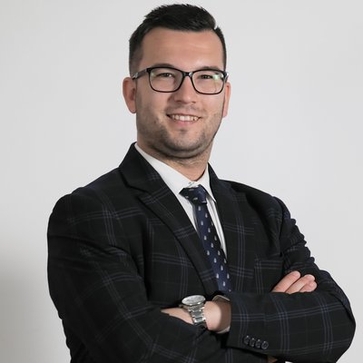 Muž s okuliarmi v obleku pózuje