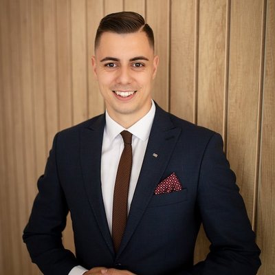 Mladý muž v obleku pri drevenej stene