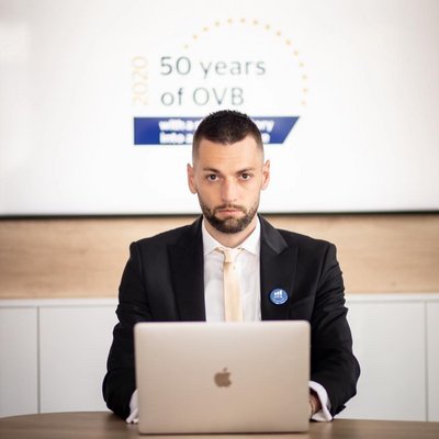 Muž za notebookom pred logom OVB