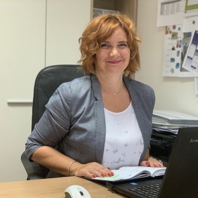 Usmiata žena pracuje pri notebooku