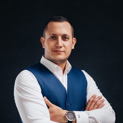 Muž s prekríženými rukami v modrej veste