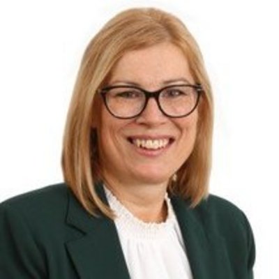 Žena v zelenom s okuliarmi a úsmevom