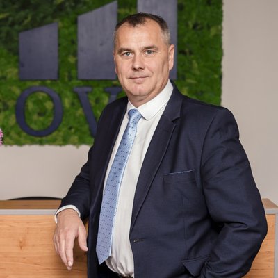 Muž v obleku pred logom OVB