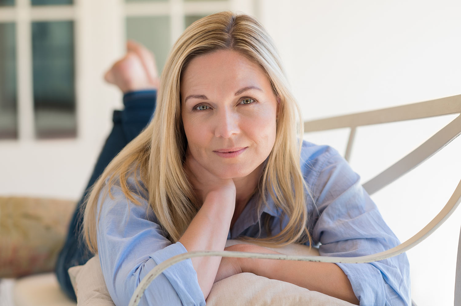 Žena leží na gauči a pozerá do kamery