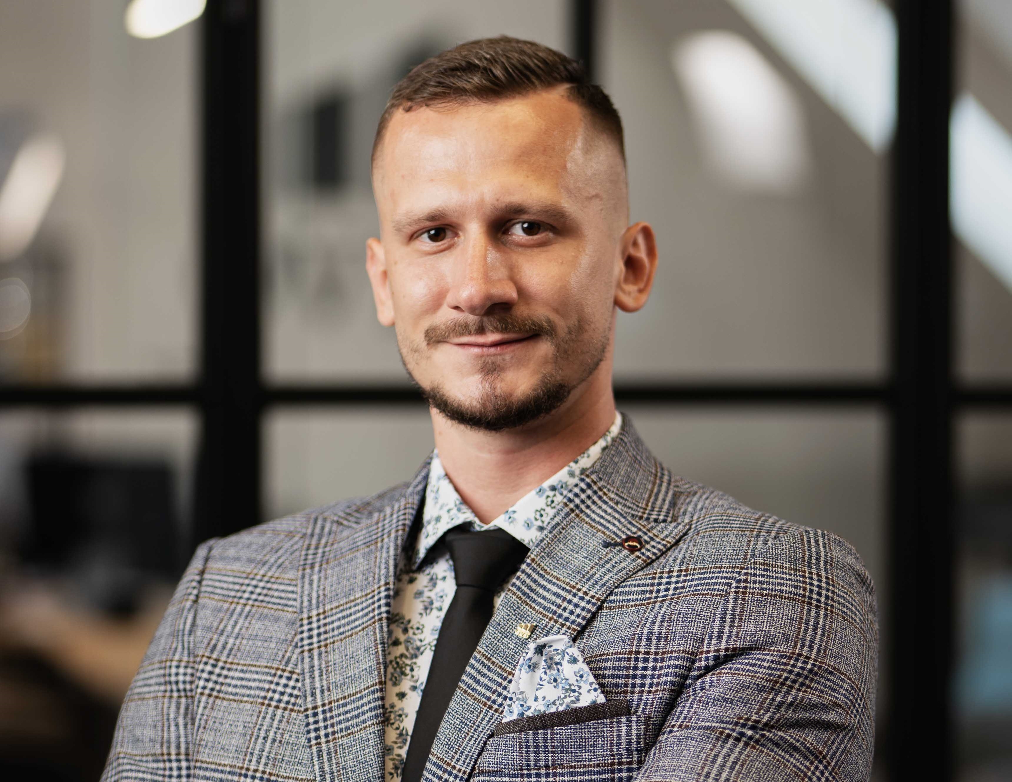 Muž v obleku s úsmevom v kancelárii