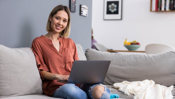Žena pracuje z domu s laptopom na pohovke 