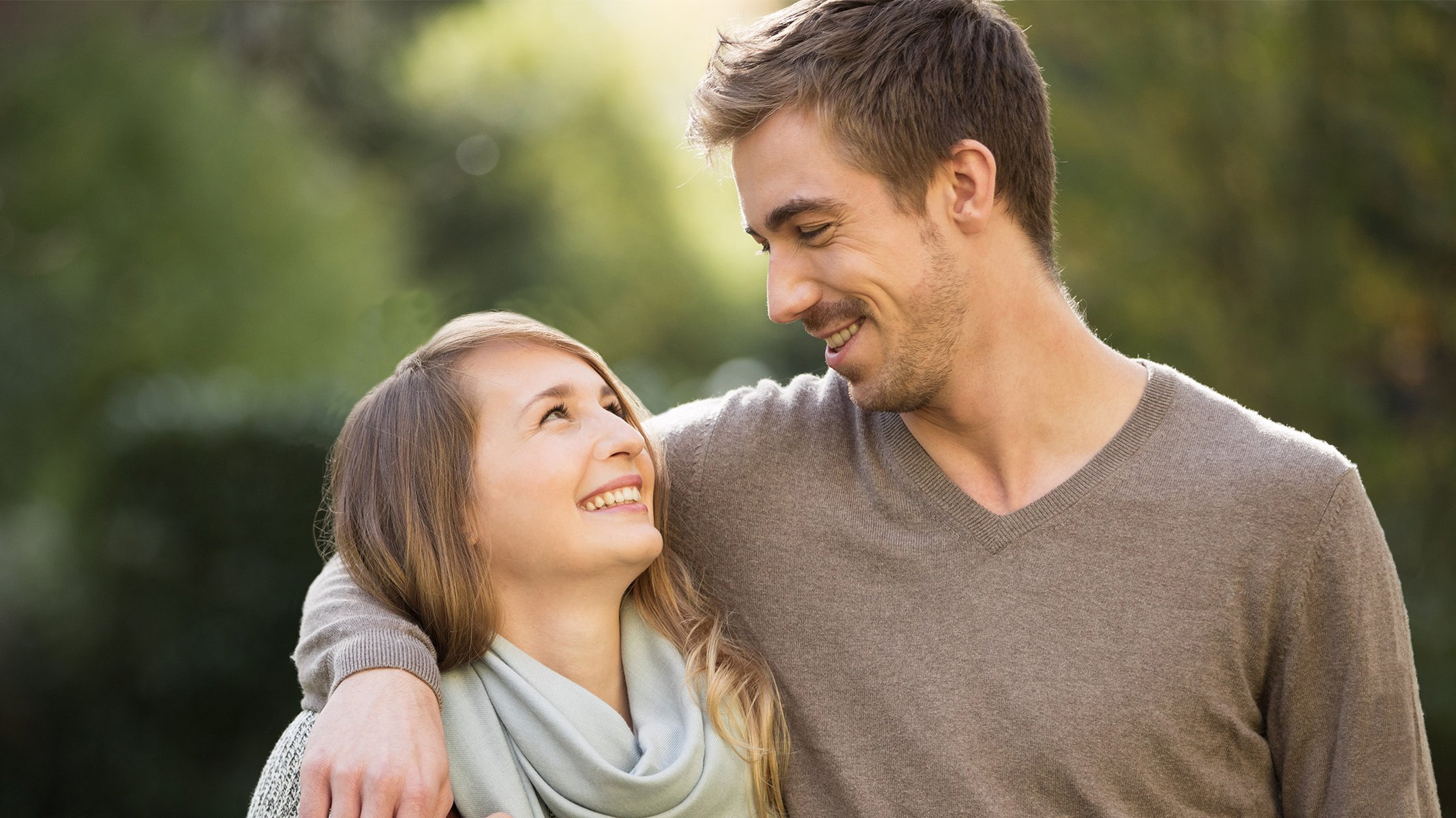 Mladý pár sa veselo usmieva a objímá sa.