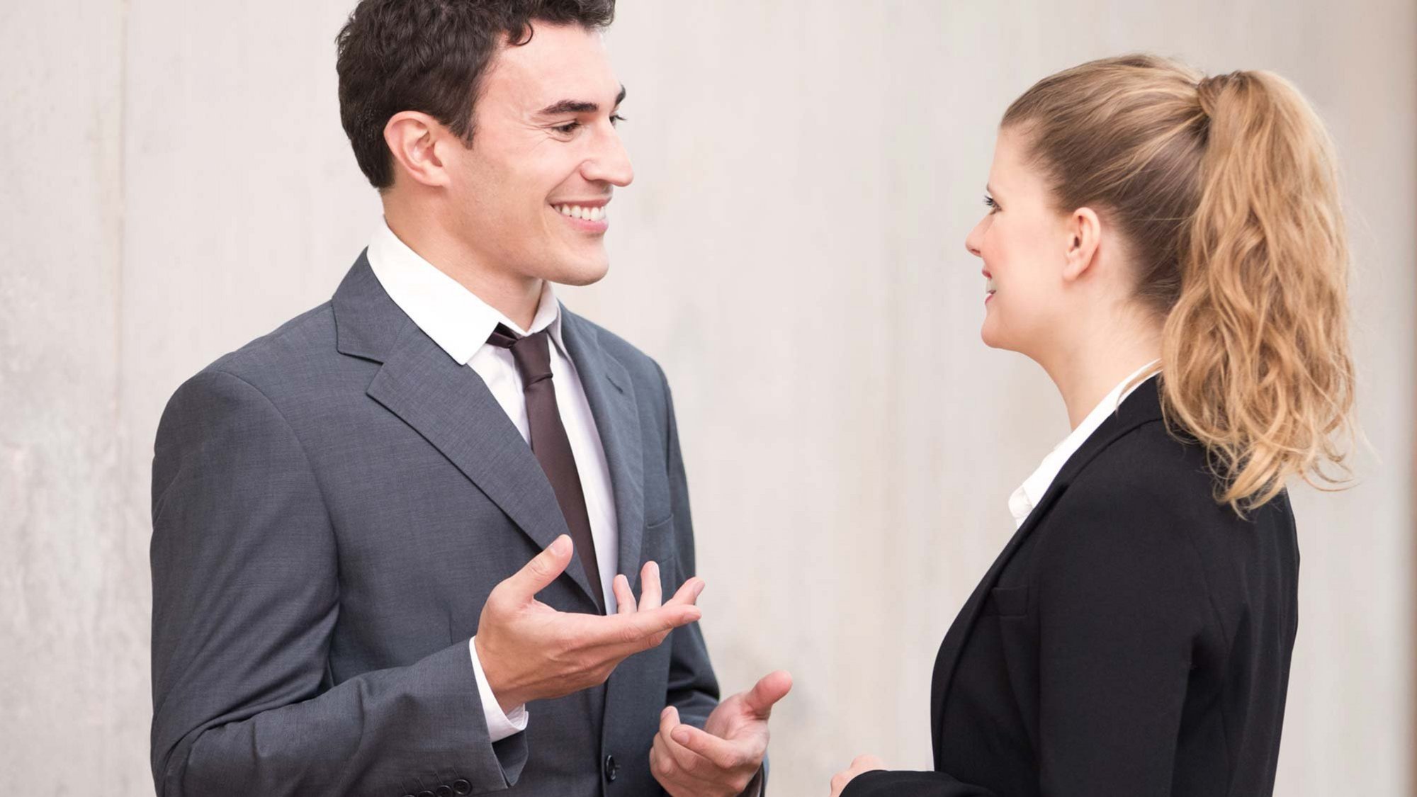 Muž a žena v business oblečení sa rozprávajú na chodbe v kancelárii.